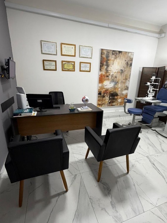 Mesa de atendimento do consultório, com certificados na parede