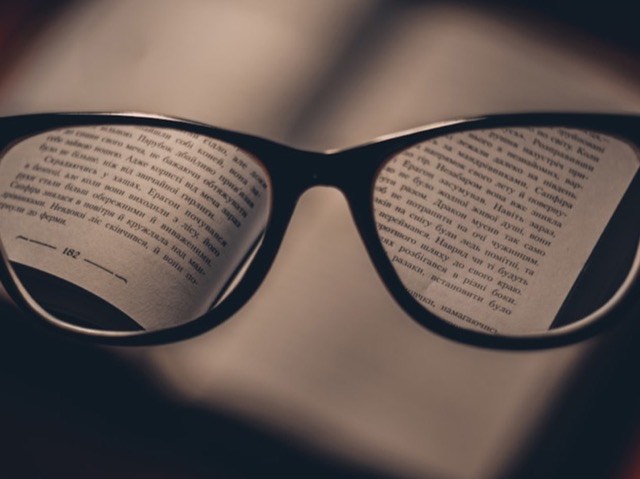 Óculos sobre um livro: o texto aparece nítido através das lentes e borrado fora delas